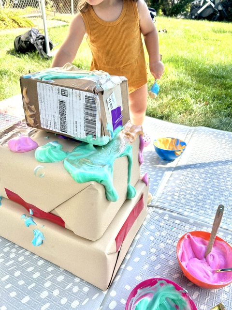 Toddler stacking and painting cardboard boxes