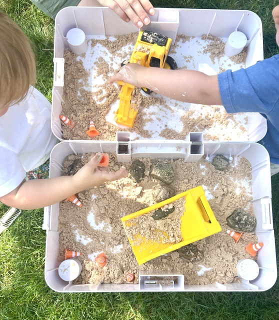 Children digging in a kinetic sand construction bin