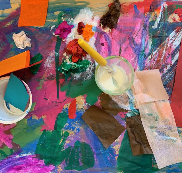 A vibrant art table covered in painted papers and creative materials