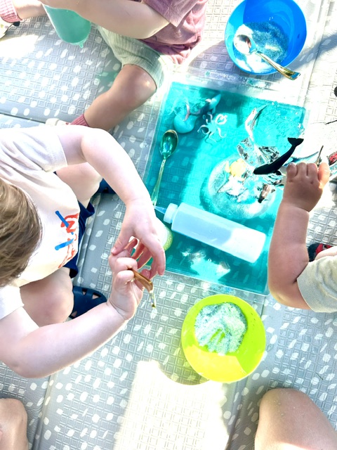 Children exploring a blue ocean sensory bin with sea creatures