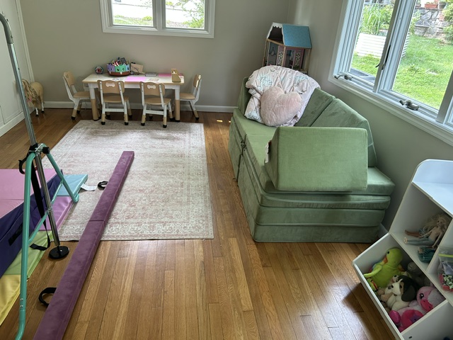Cozy playroom corner with rug, fold-out couch, and dollhouse